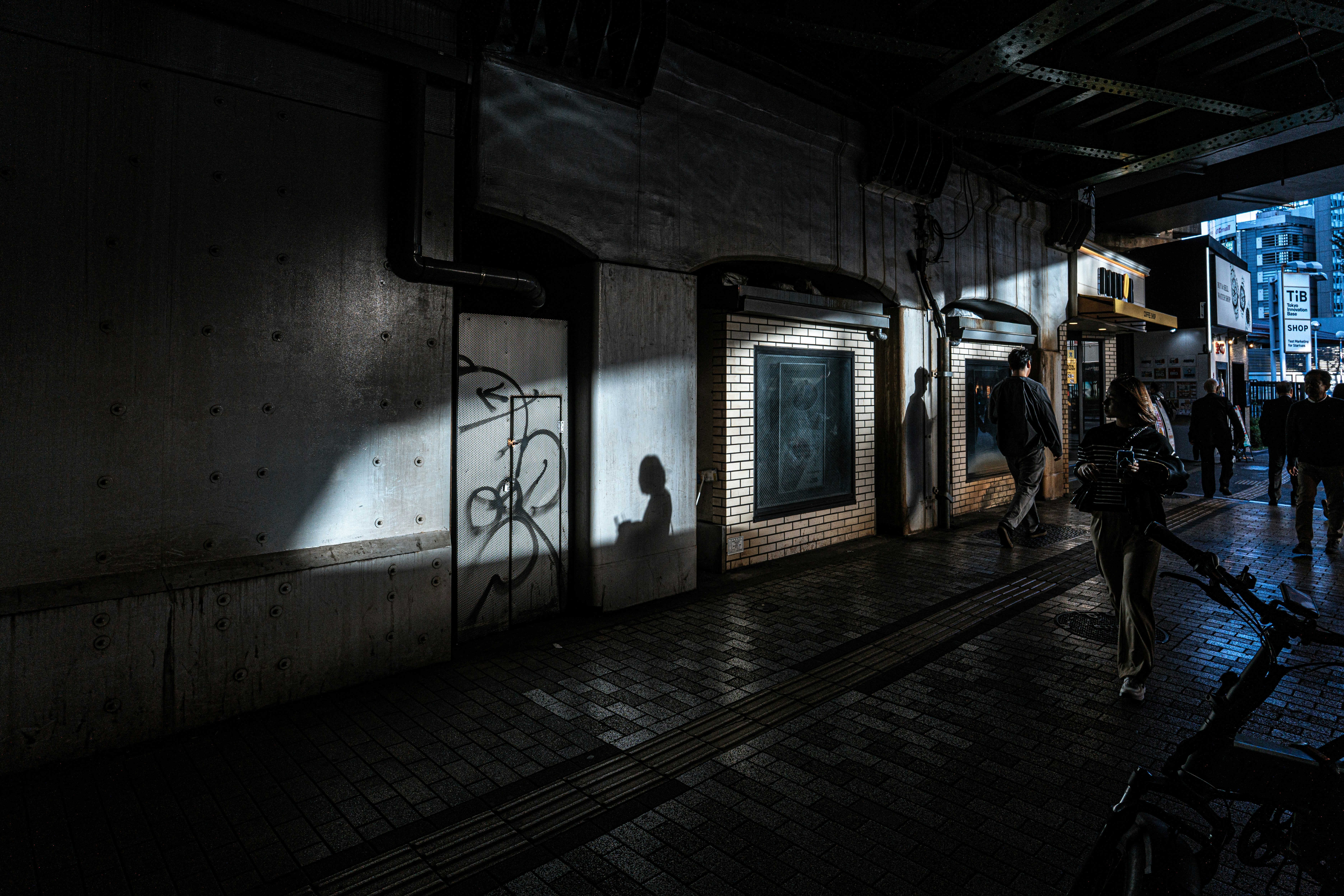 Dark alleyway with graffiti and distant figures.