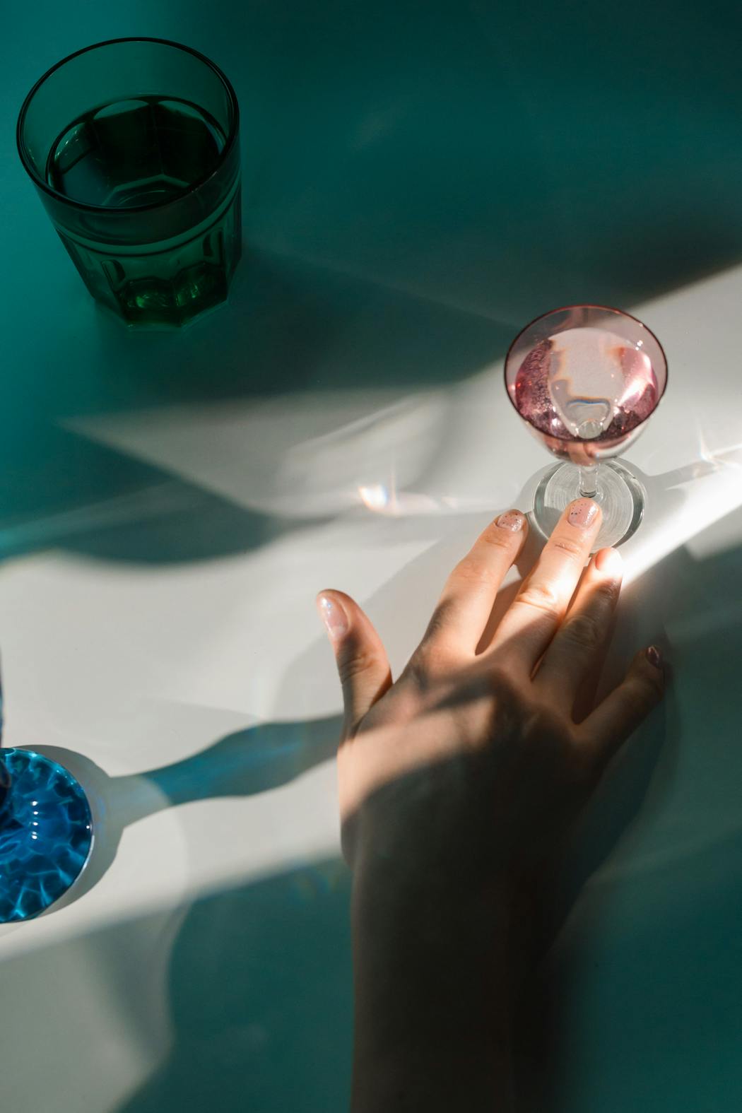 Hand pushing a pink glass