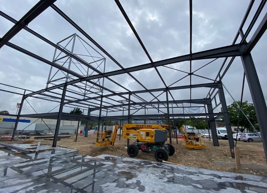 Montage de la charpente métallique avec engins de levage sur chantier.