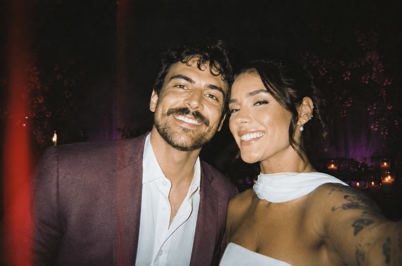 Casal sorrindo numa selfie durante a festa de casamento, à noite