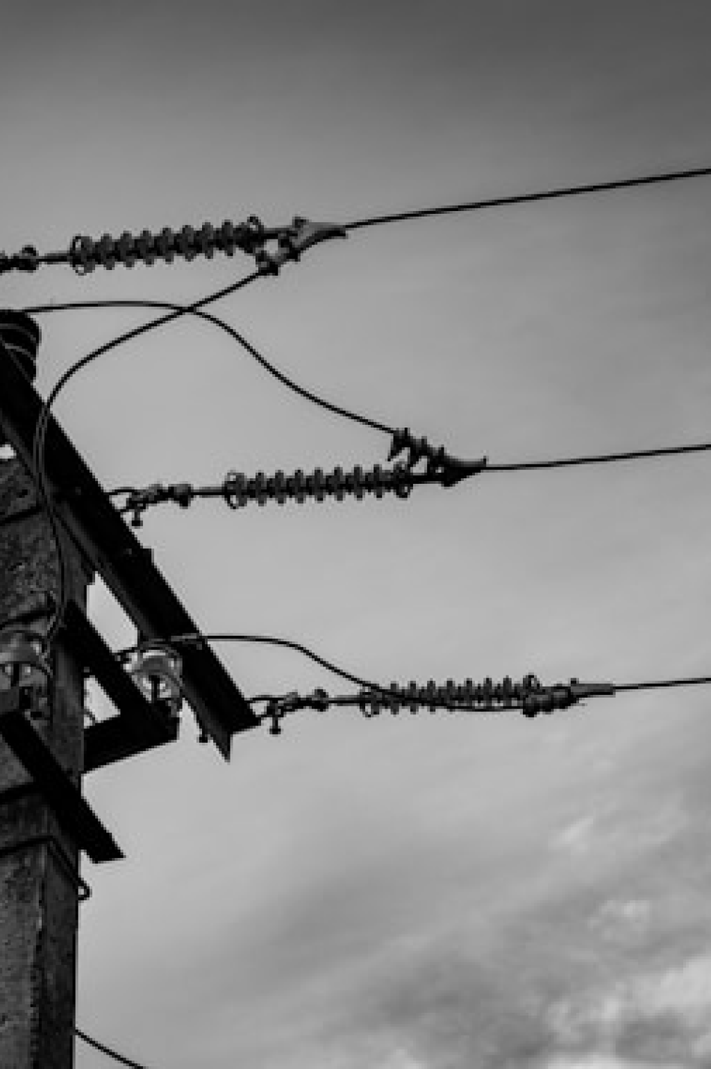 Columna eléctrica con conexionado y cielo nublado en blanco y negro