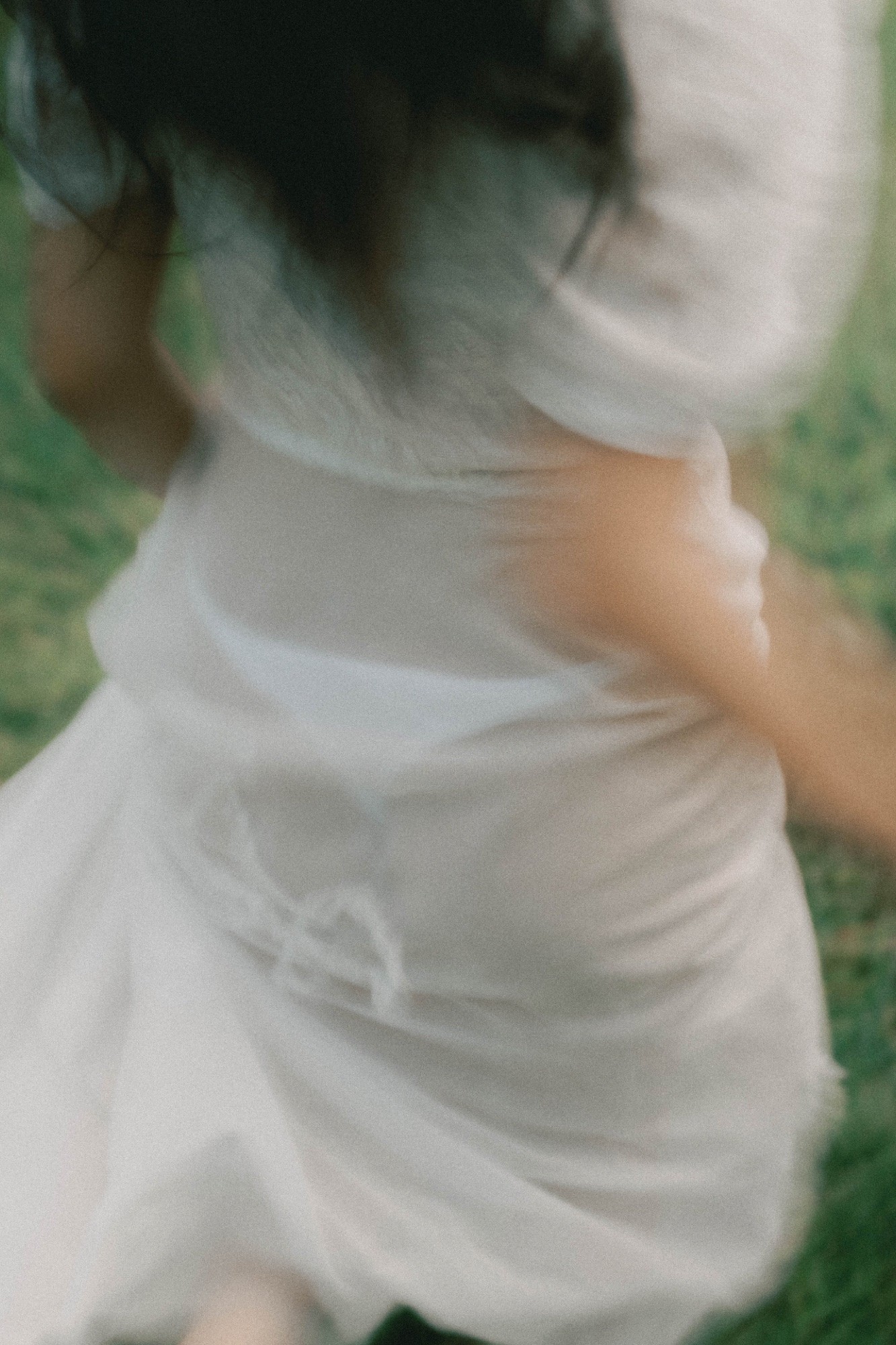 White dress turning on grass, caught in motion blur
