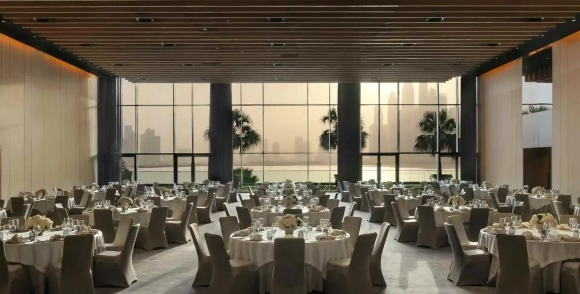 Large banquet hall with round tables set, city view