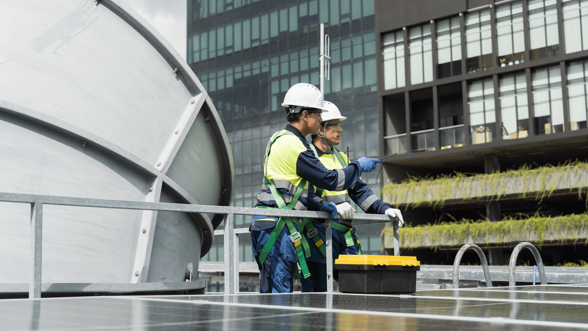 Engineers examining a large commercial HVAC installation on a rooftop, reviewing system layouts and performing maintenance checks.