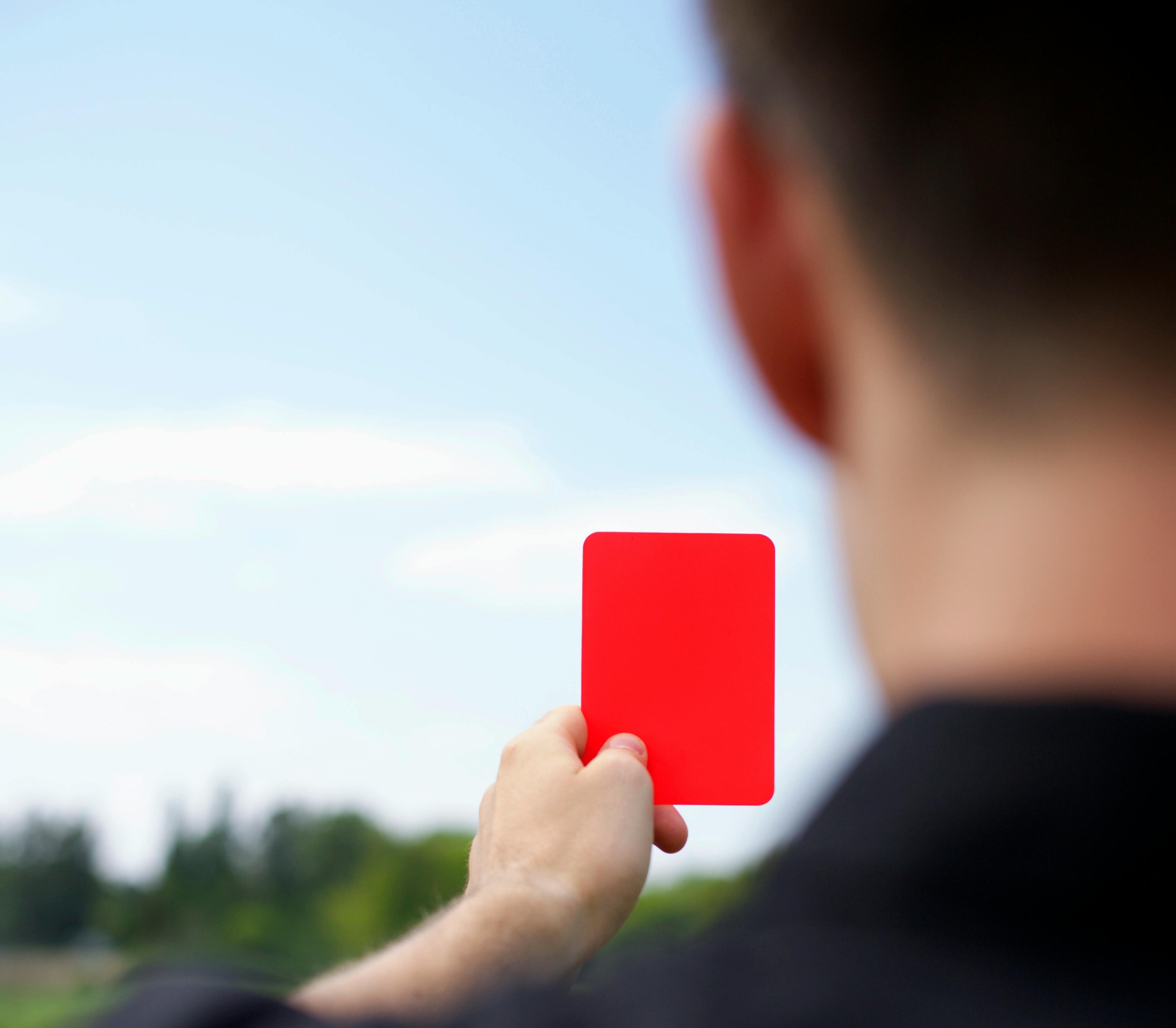 An umpire giving a red card pentalty, symbolising how facilities receive regulatory penalties from non-compliance.