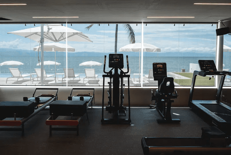 Fitness room with cardio machines and a glass wall facing the sea