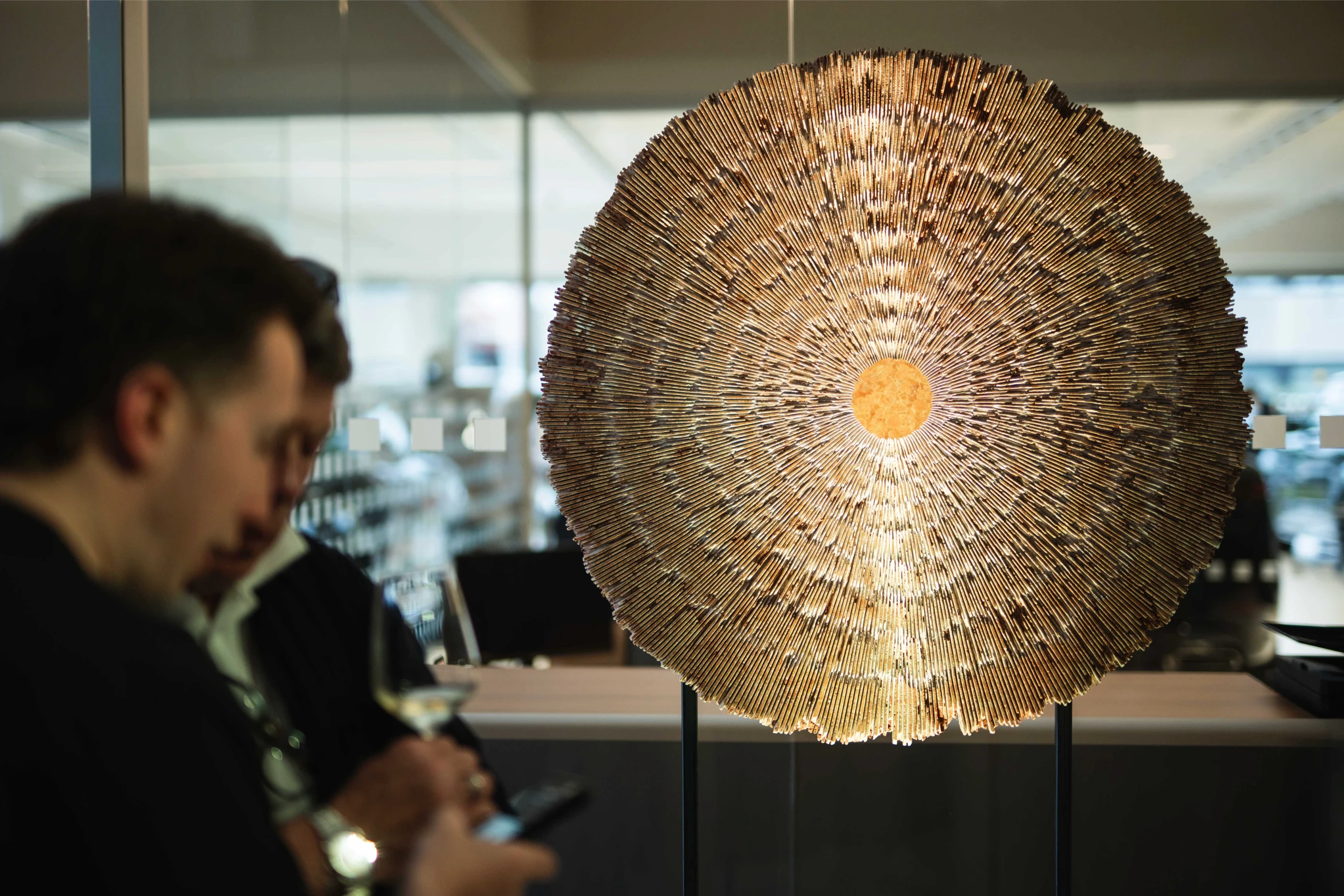 Opera di arte OCTA - Land Rover realizzata da iStone Arte installata in showroom aziendale durante evento inaugurale, sculture radiali illuminate e pubblico in interazione con le opere