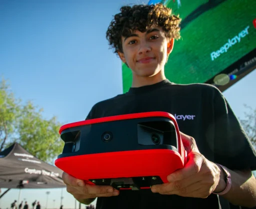Young soccer player holding a Reeplayer camera, showcasing the advanced recording equipment used for capturing game footage