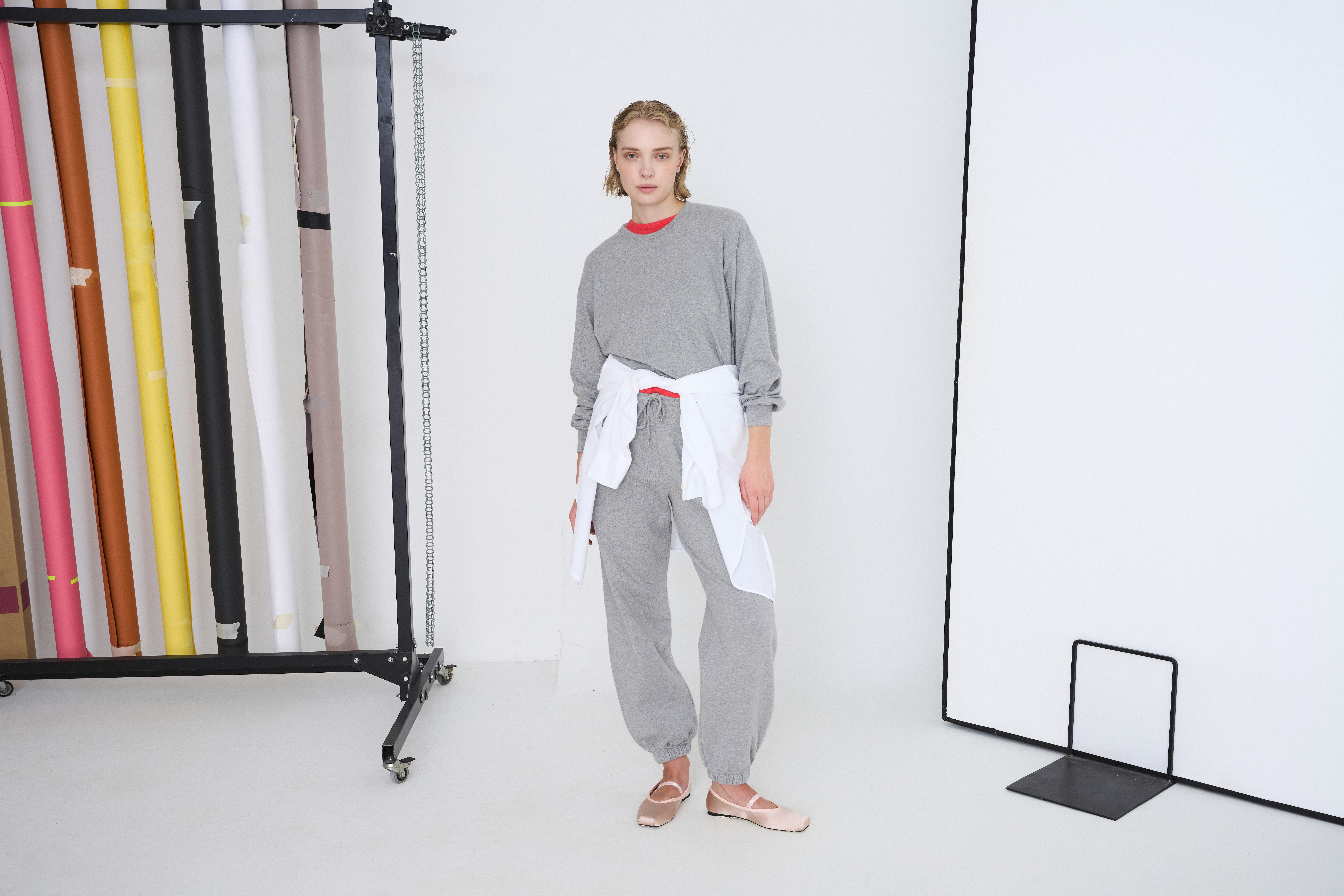 Dans le lookbook Colorful Standard, la mannequin porte sweat et jogging gris clair et une pièce blanche autour de la taille