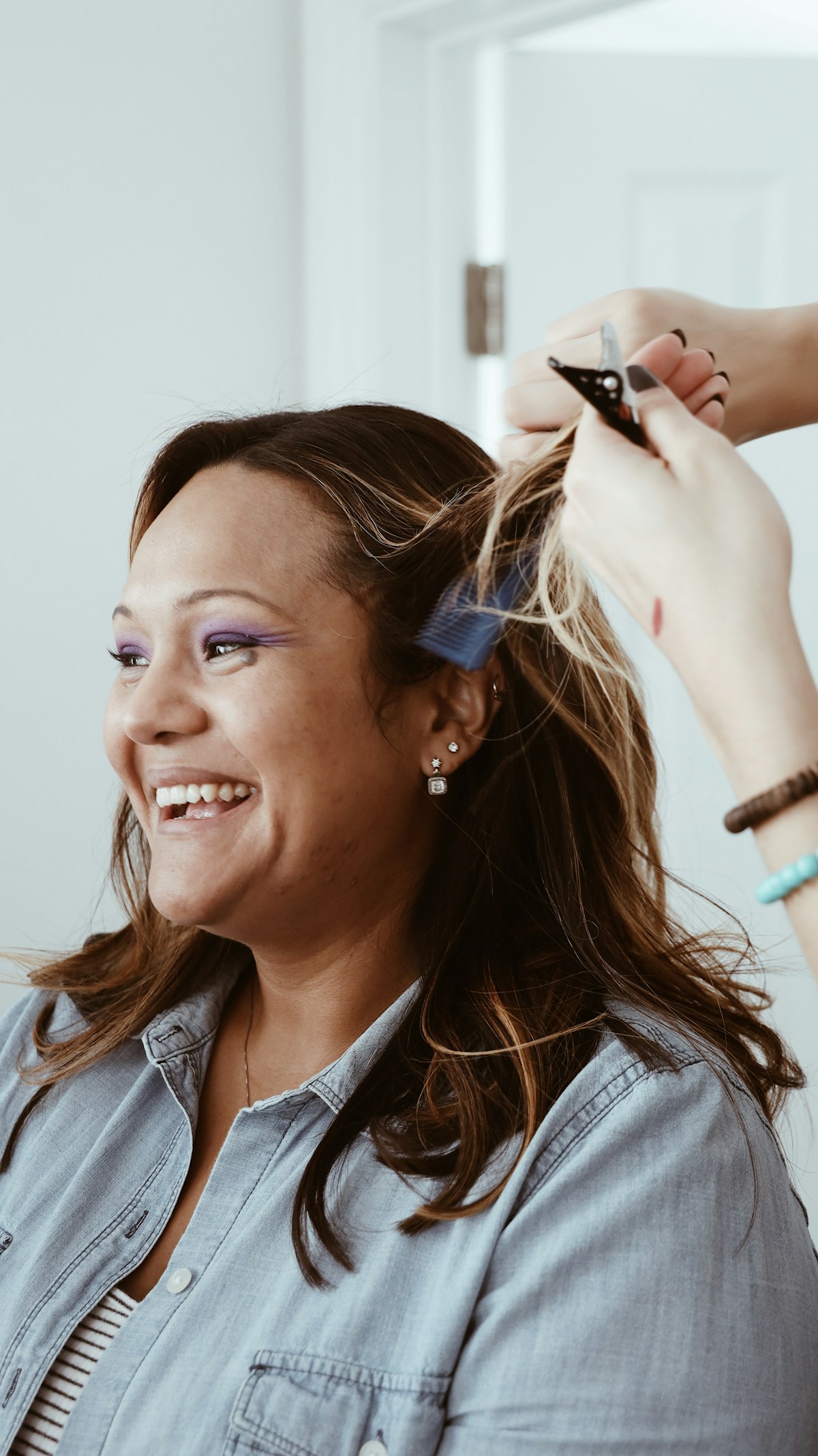 A smiling client having colour painted onto her hair in foils
