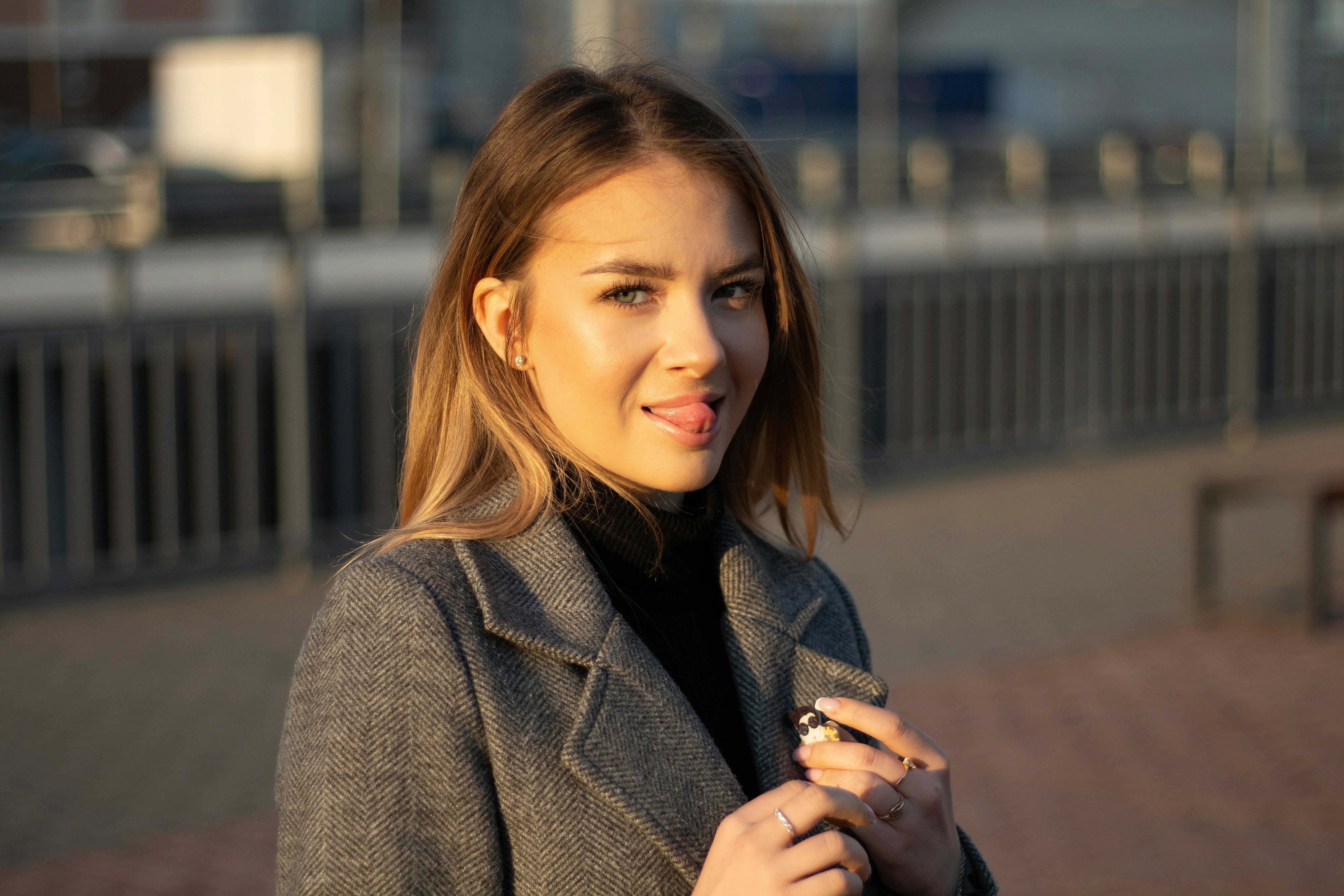 a woman in a coat is holding a cigarette