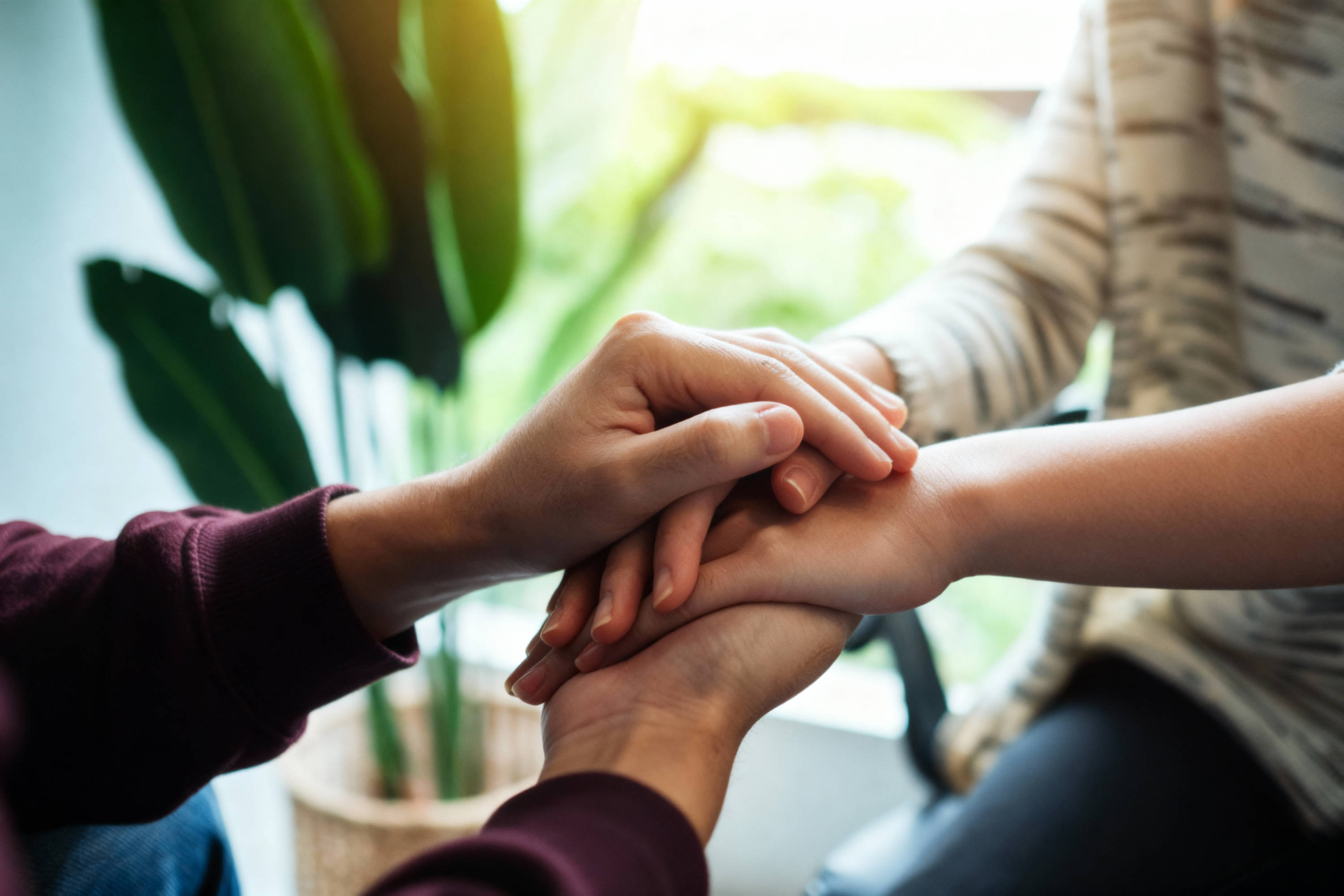 Zwei Personen legen ihre Hände übereinander als Zeichen von Zusammenhalt und Gemeinschaft