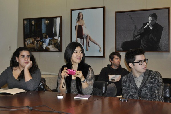 photo of a group of people taking pictures and notes while listening to a lecture.