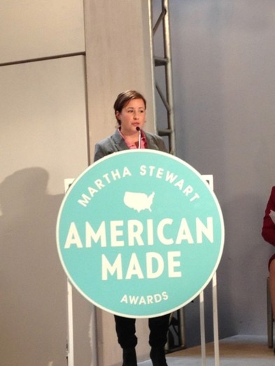 a woman giving a speech on the stand with the Martha Stewart American Made awards logo