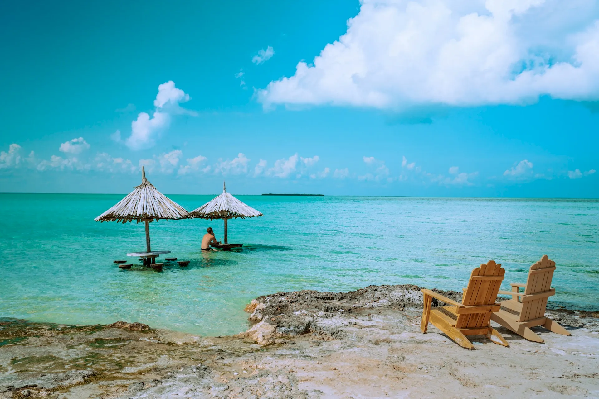 Two chairs looking out into the ocear with tables in the ocean in Belize