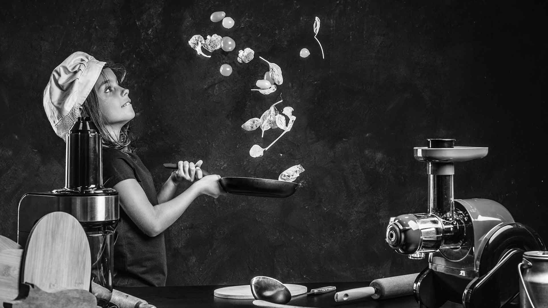 Юна кухарка готує на сковорідці біля побутової техніки