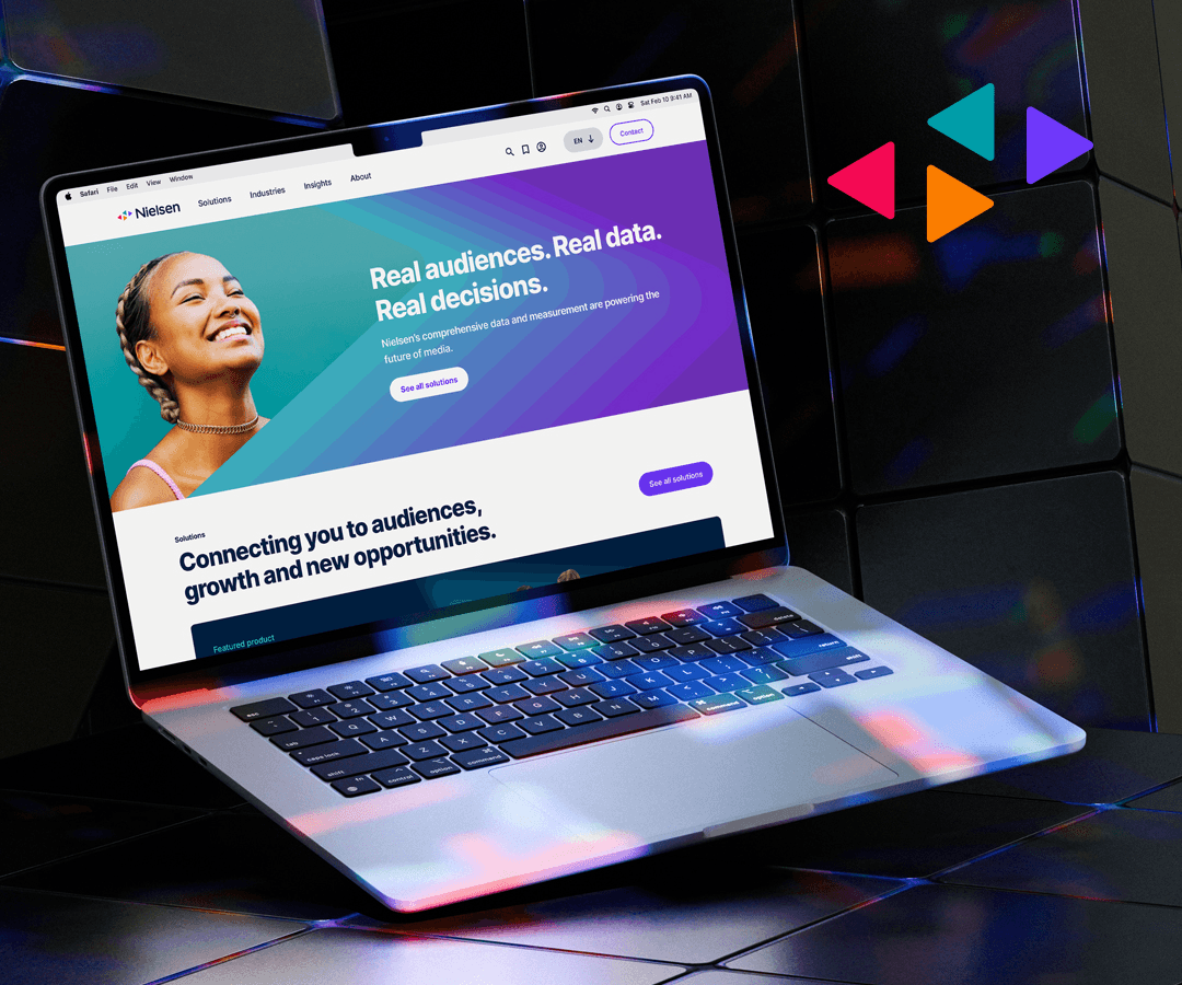 Image of Nielsen homepage on a macbook that is sitting on top of tiles with reflections from colour lights