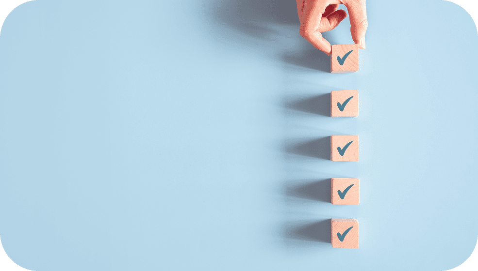 Hand stacking wooden blocks with checkmarks, symbolizing the importance of consistency and tracking daily study habits.
