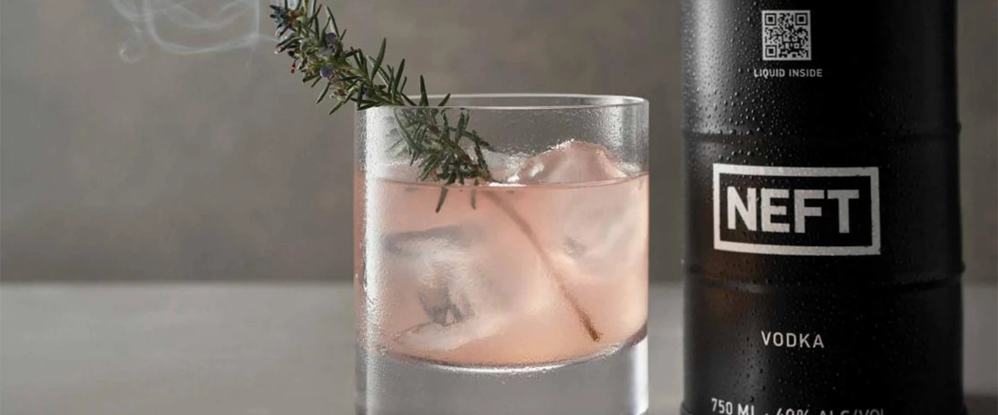 Violet Frost cocktail drink next to a NEFT vodka barrel.