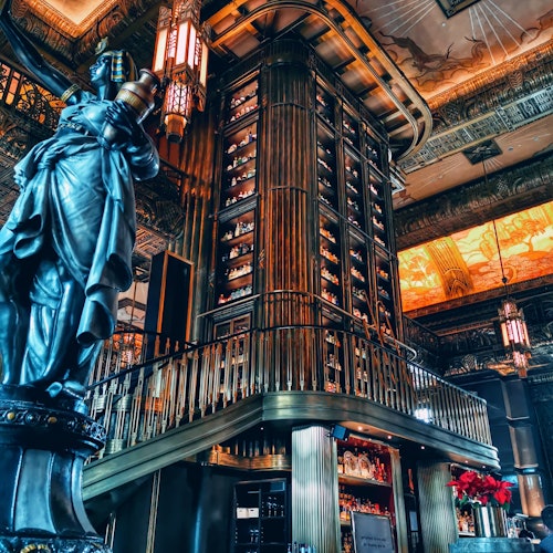 豪华的内饰特点包括一个高大的圆柱形木制酒架、精致的天花板设计以及一个持火炬的长袍雕像。