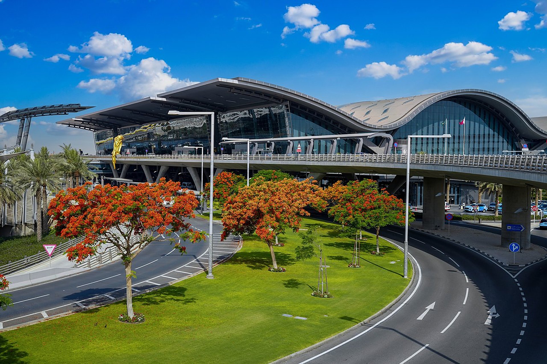 Le terminal de l'aéroport international Hamad, à Doha, ses arbres aux fleurs rouges et son ciel bleu, le point de départ de vos vacances en famille