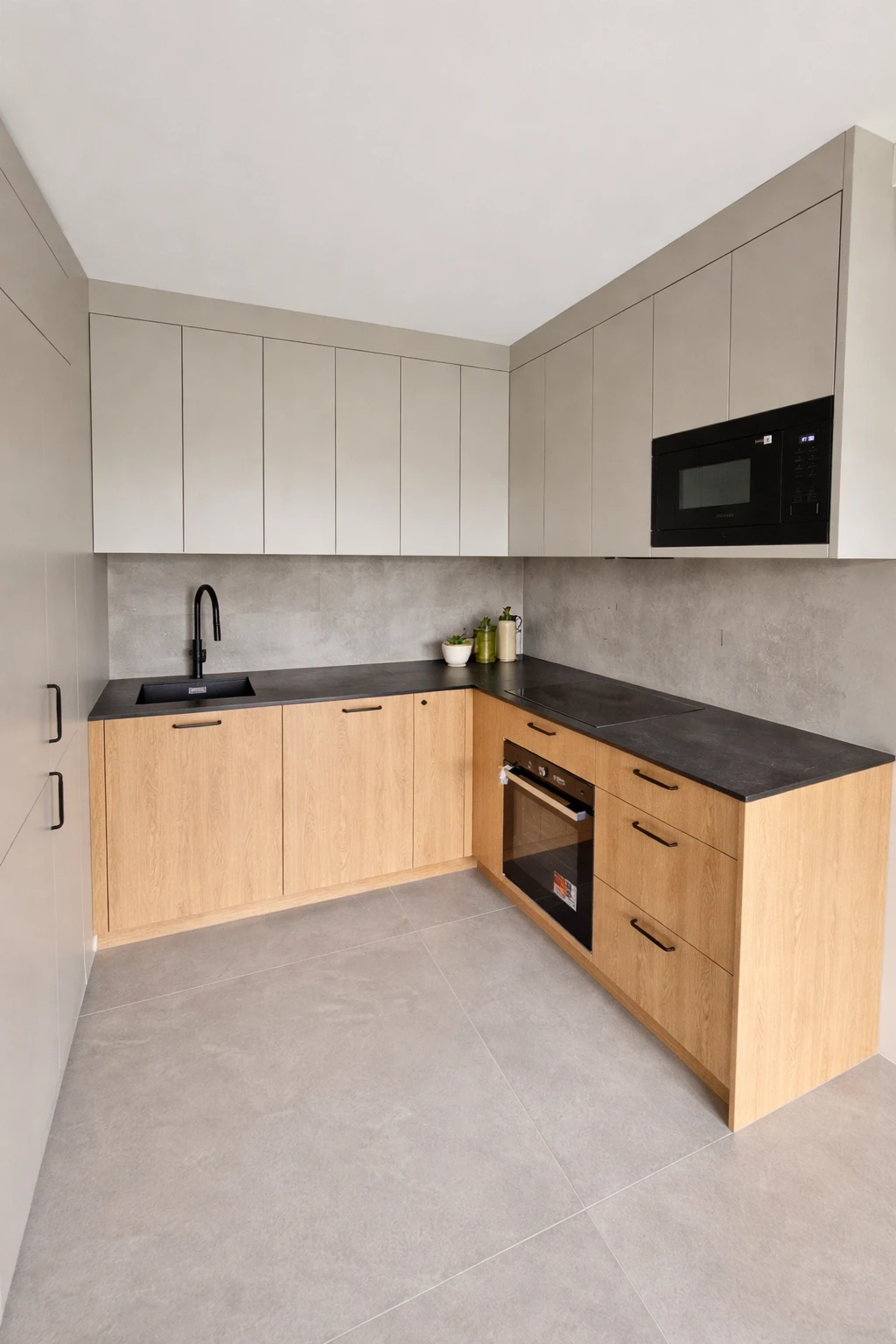 Nowoczesna kuchnia w kształcie litery L z szarymi frontami i czarnym zlewem.