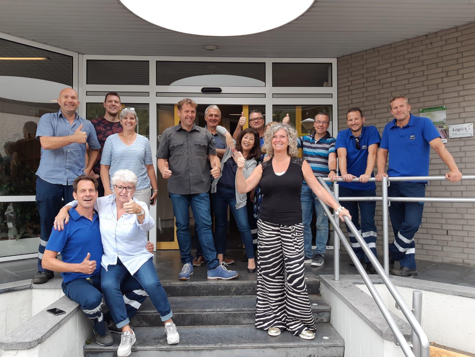 A person sits at a desk and looks at a laptop screen showing two people in a video conference.
