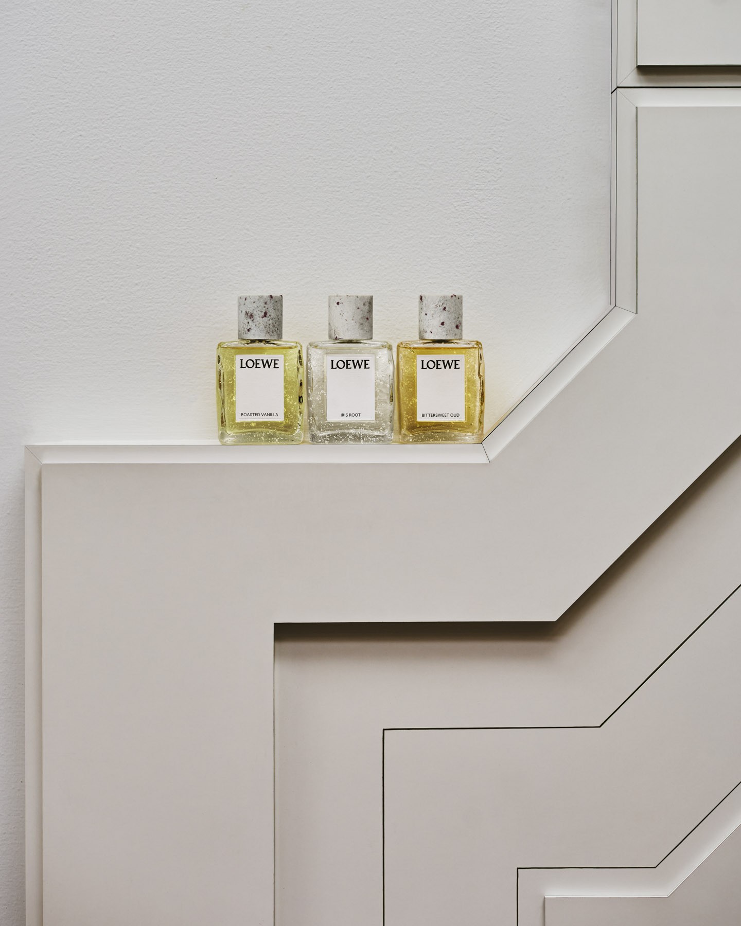 Three LOEWE Crafted Collection fragrances displayed on a sculptural staircase inside Antonio Lamela’s architectural studio in Madrid.