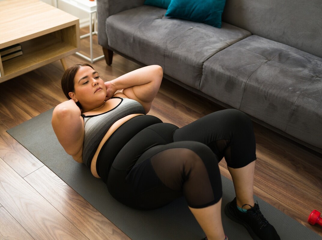 woman doing situps for strength training to lose weight at home in her living room