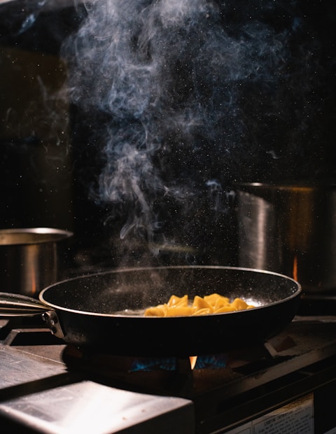 Dark moody kitchen, cast iron pan on flame