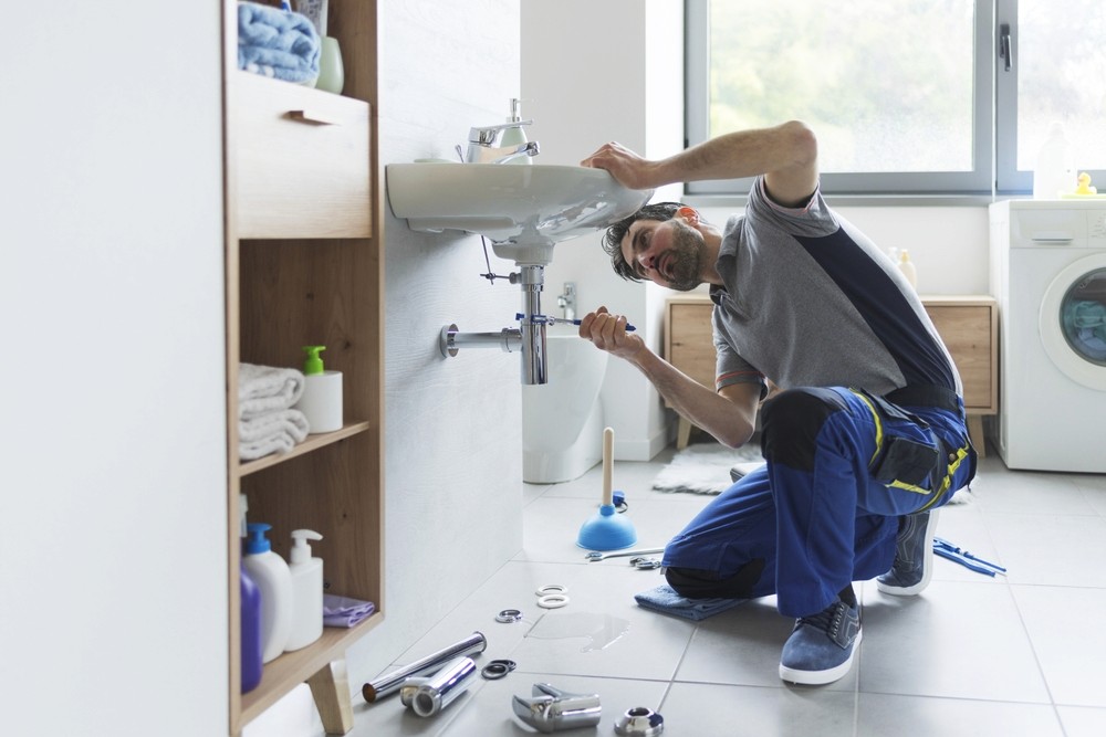 Professional plumber checking drain pipes at home and using pliers