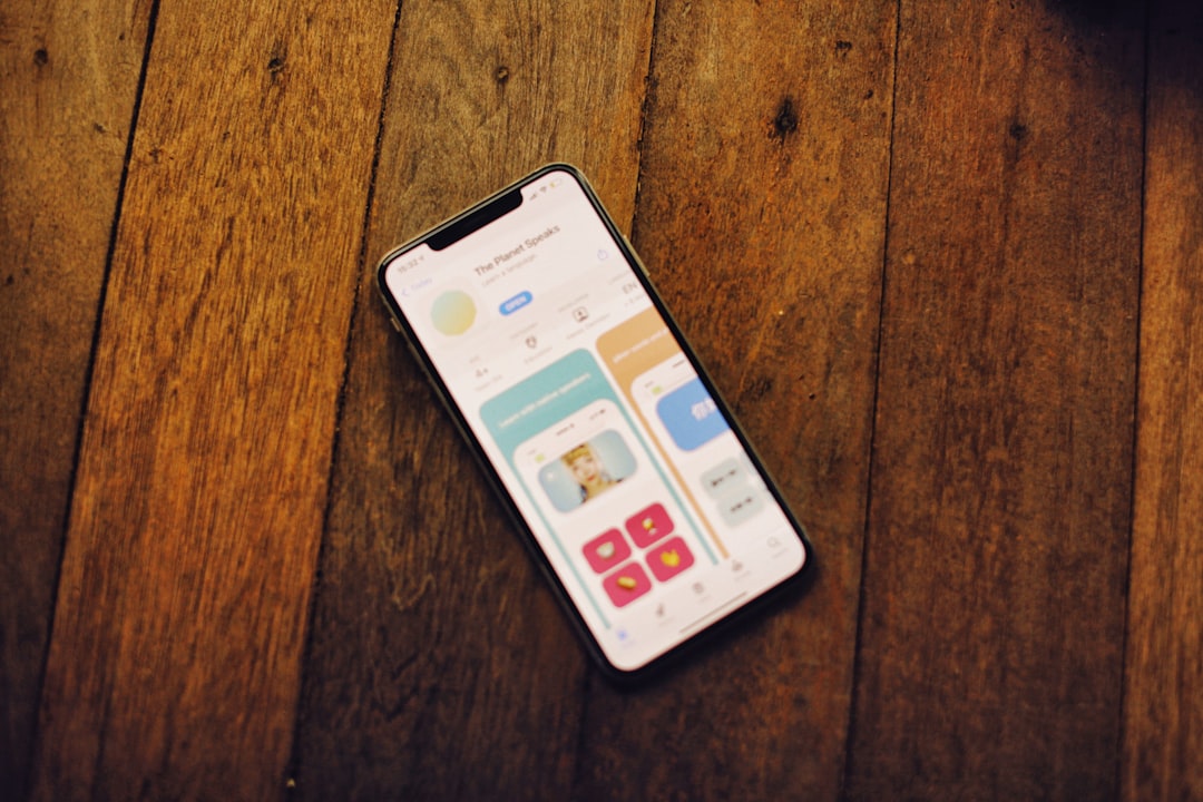 A smartphone displays a colorful app on wood.