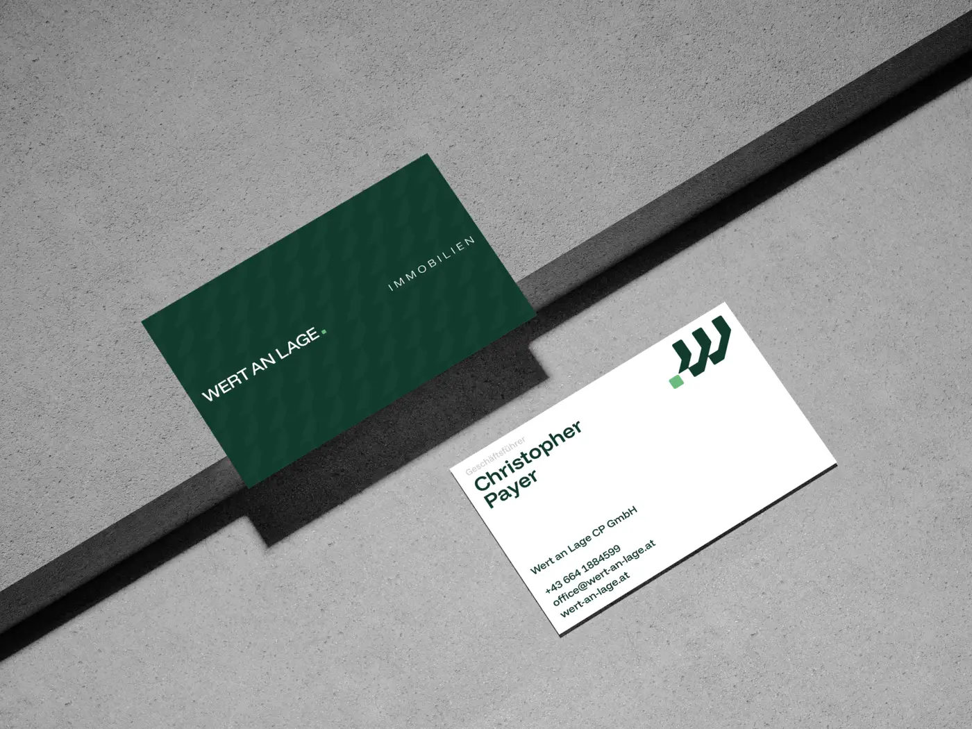 Ein Bild von der Vor- und Rückseite der Visitenkarte von Wert an Lage auf einem Betonboden.