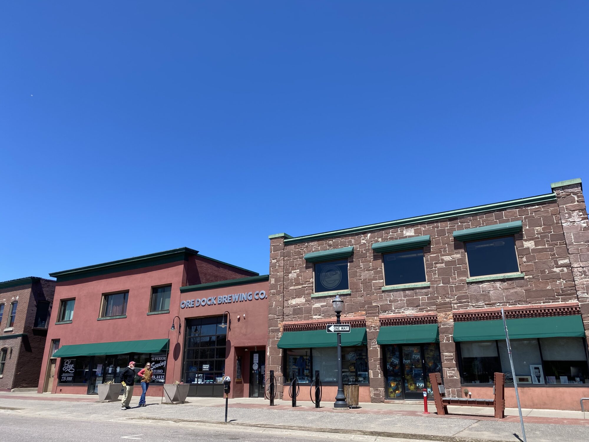 the interior of six spoke brewing company, with wooden picnic tables, kegs in the background ,and lots of natural light.