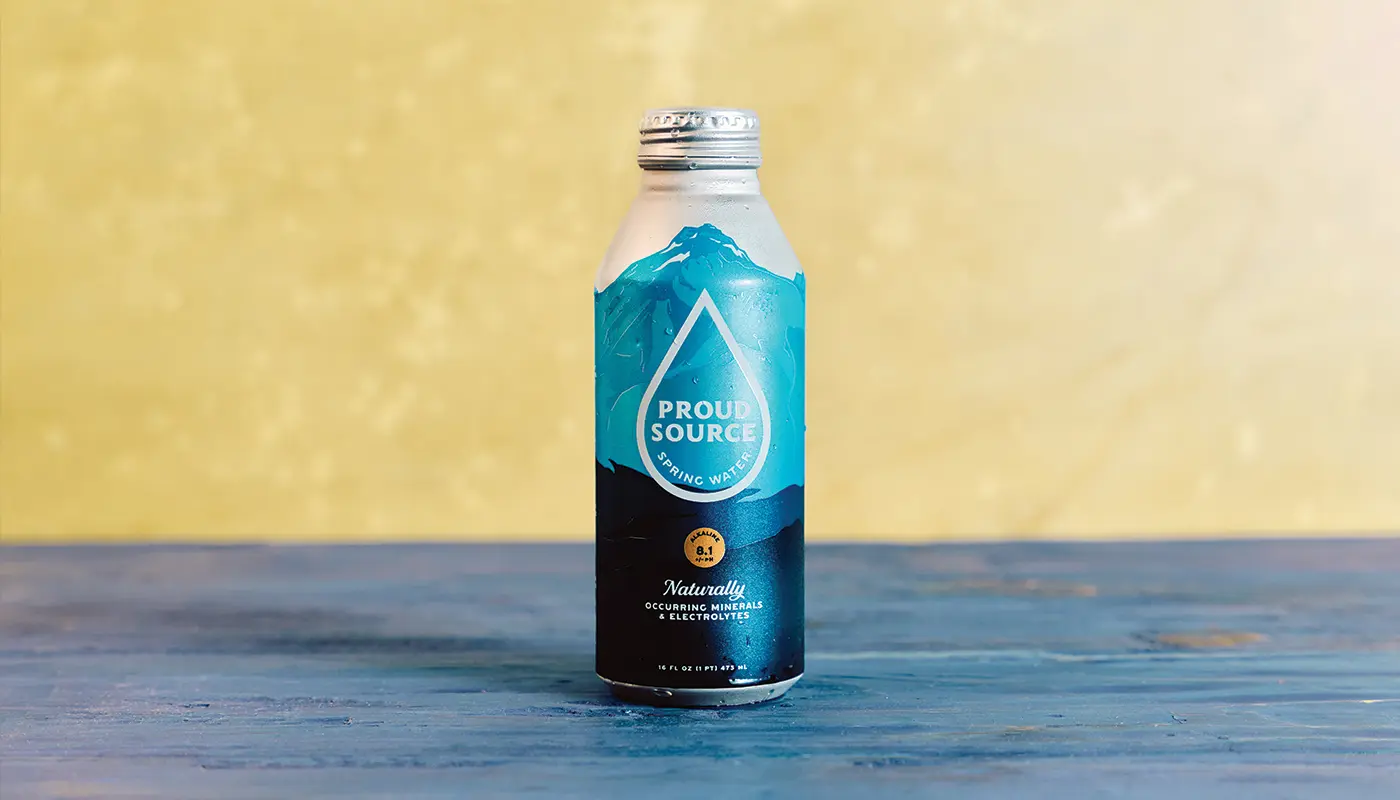 A bottle of water on blue wooden boards against a yellow wall.