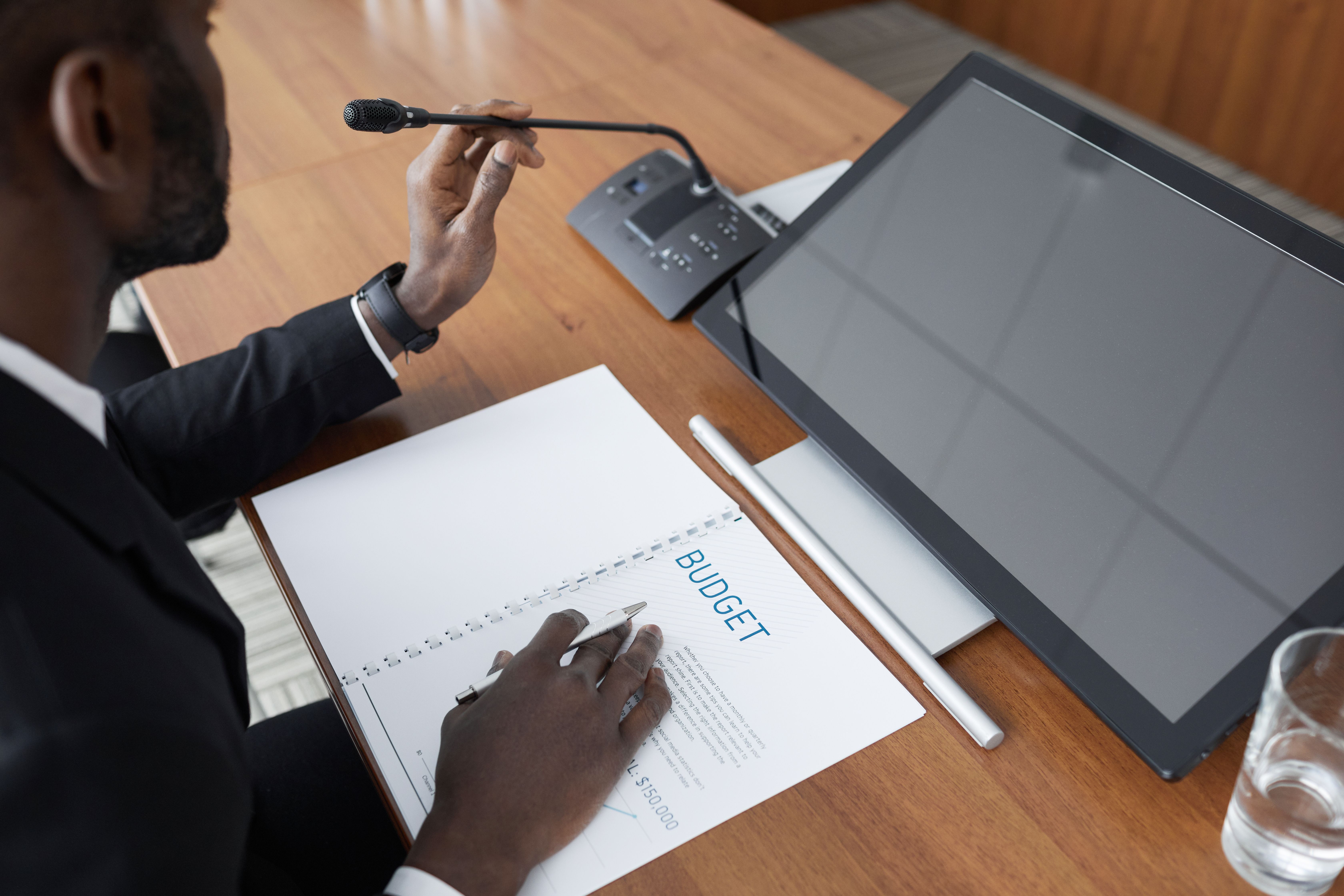 african-american-man-in-a-meeting-reviewing-a-budget-document-with-a-microphone - werner-pfennig (pexels)