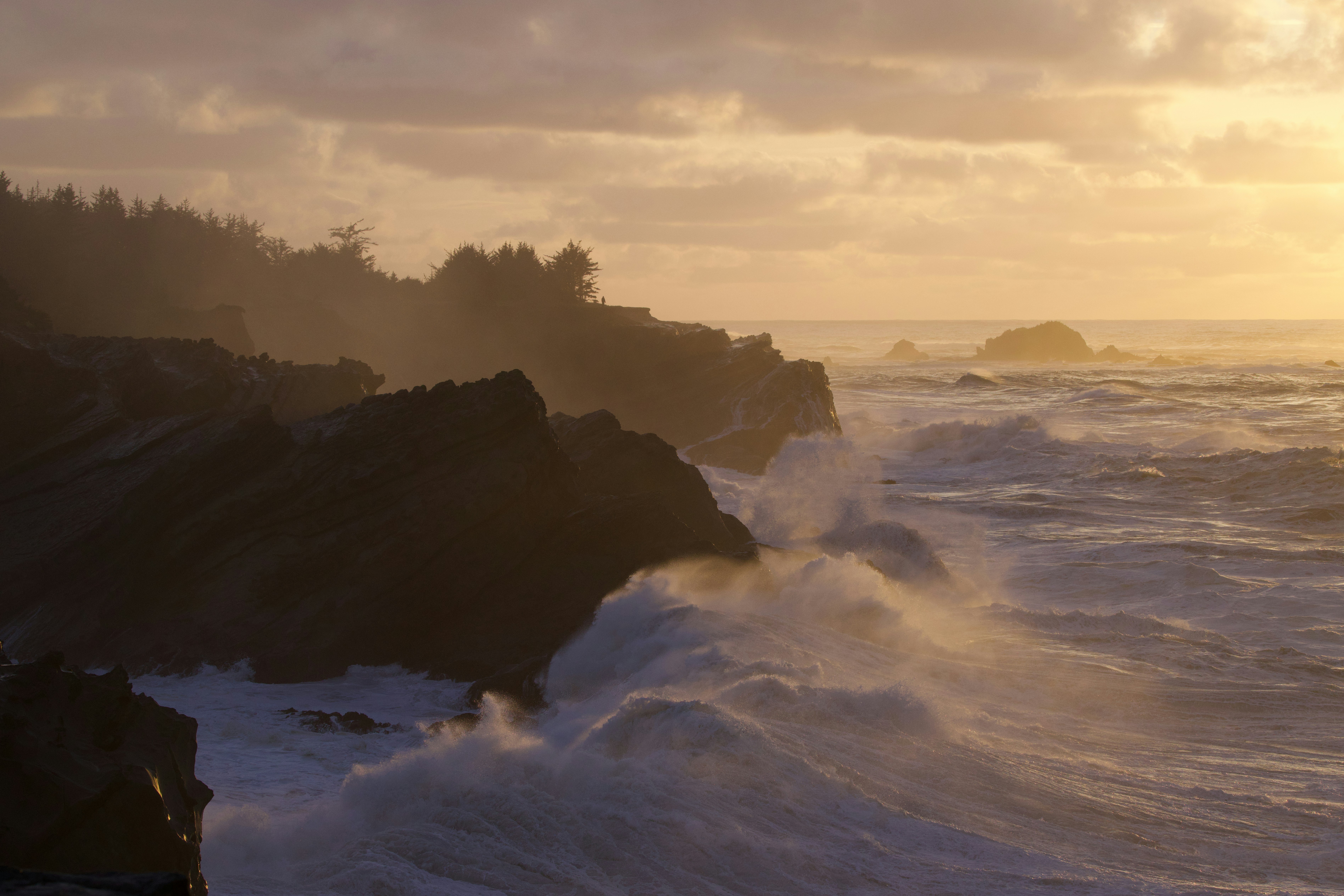 Waves crash against rocky cliffs at sunset