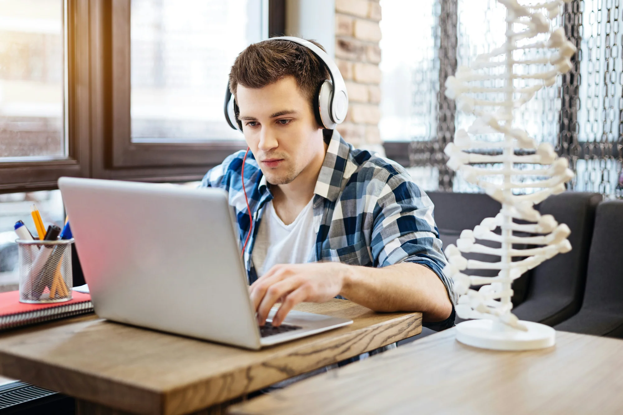 Person wearing headphones working focused on laptop at home workspace