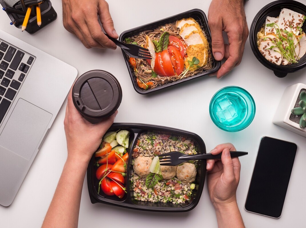 two colleagues having healthy meal prep lunches together at work as part of their plan for how to lose weight without exercise in a week