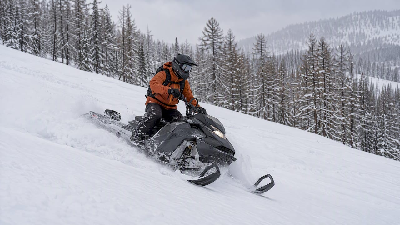Snowmobile rider making a turn in deep powder snow
