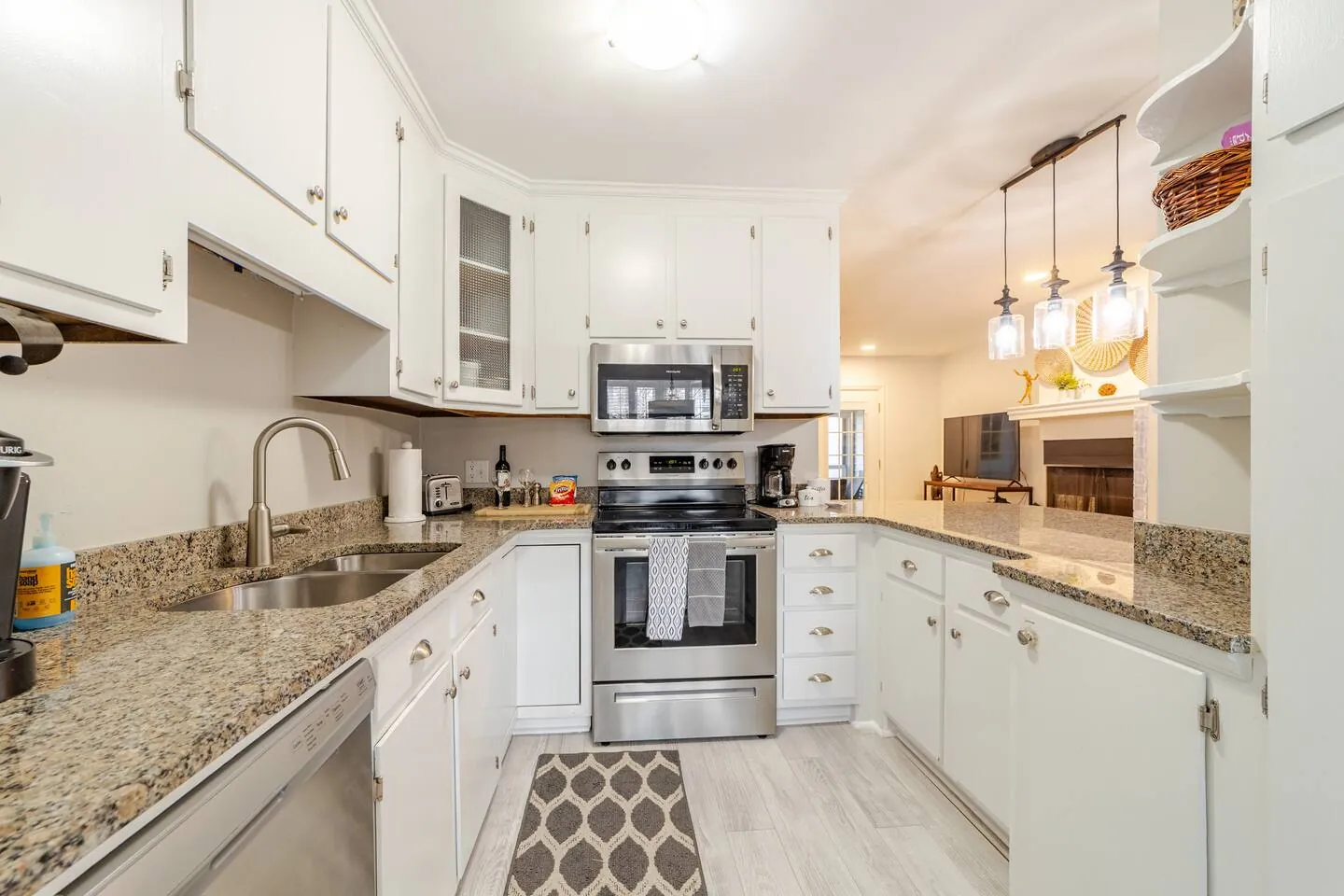 White kitchen with granite counters, stainless appliances and pendant lights