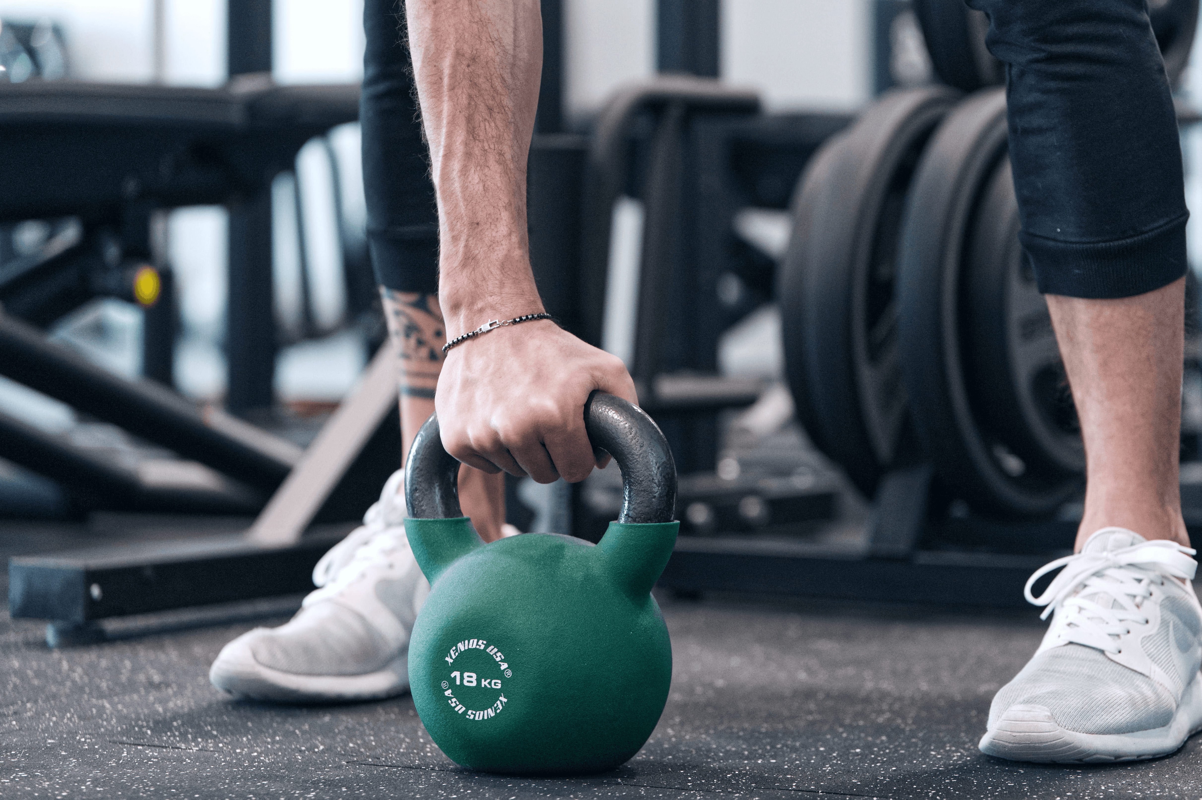 A man in a brown blazer and a woman in a light sweater sit at a desk with a laptop, discussing something. The room is dimly lit, creating a focused atmosphere.
