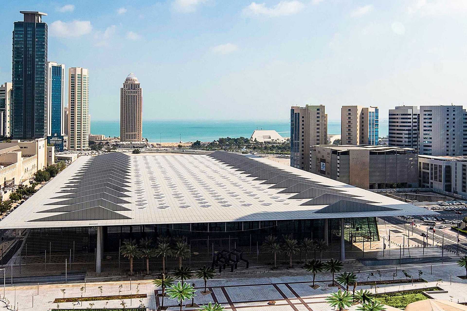 Le centre des expositions et des congrès de Doha vu d'en haut, avec les tours de West Bay et la mer au loin, l'un des lieux des grands salons professionnels
