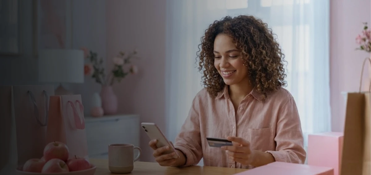 Mulher com um celular e um cartão de crédito na mão
