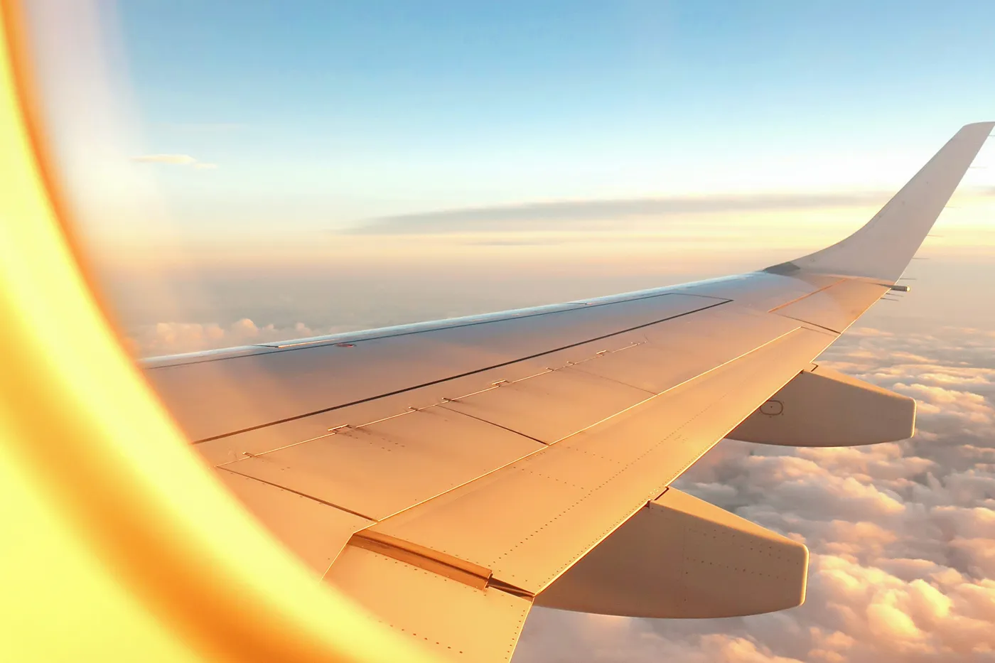 Asa de avião sobre as nuvens ao pôr-do-sol — transferes de táxi de Caminha para os aeroportos do Porto, Vigo e Lisboa a preço fixo · Táxi Afonso 06