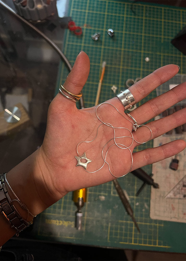 Hand holding 950 silver jewelry with a workshop background