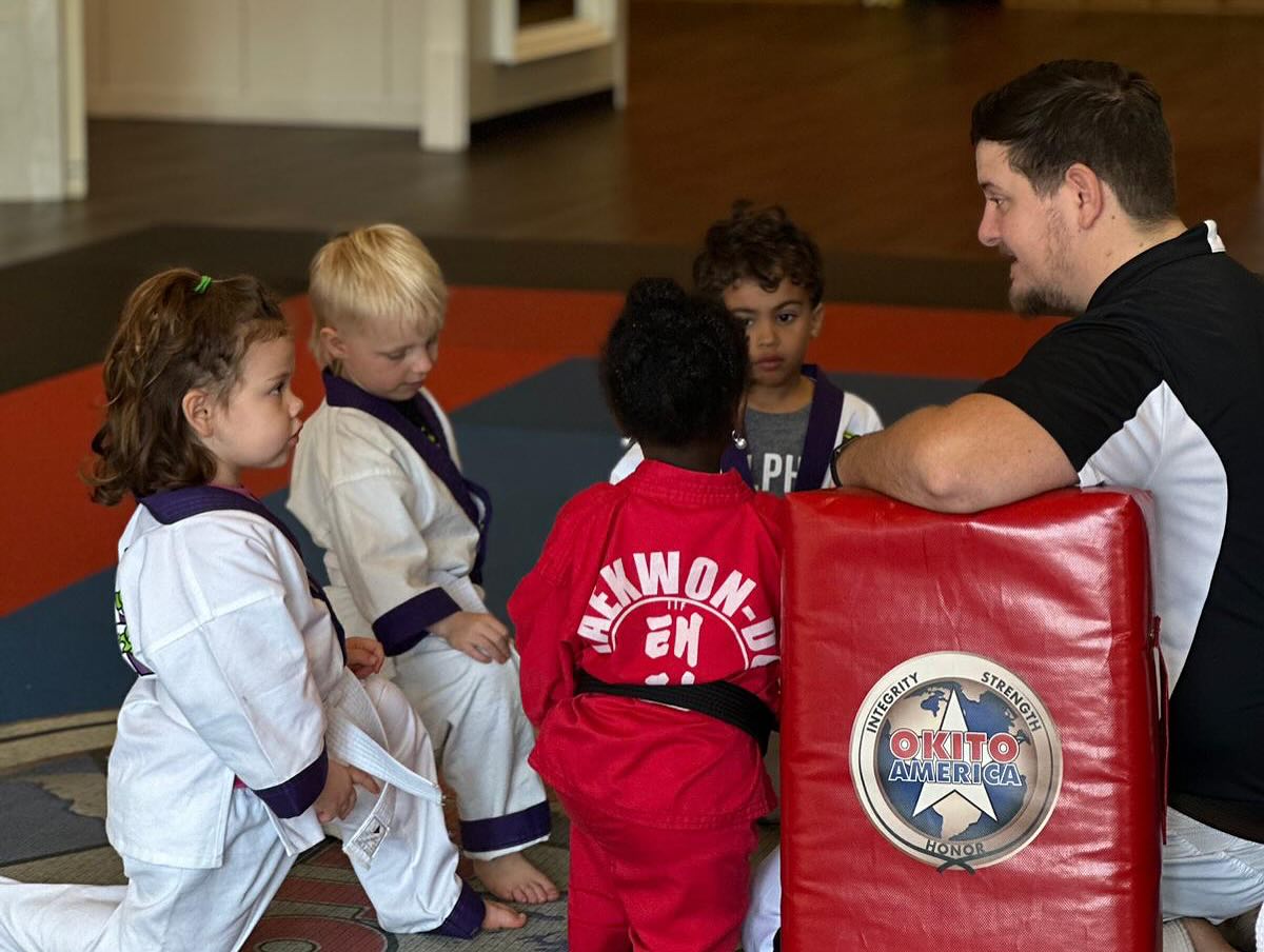 Instructor talking to a group very young taekwondo students.