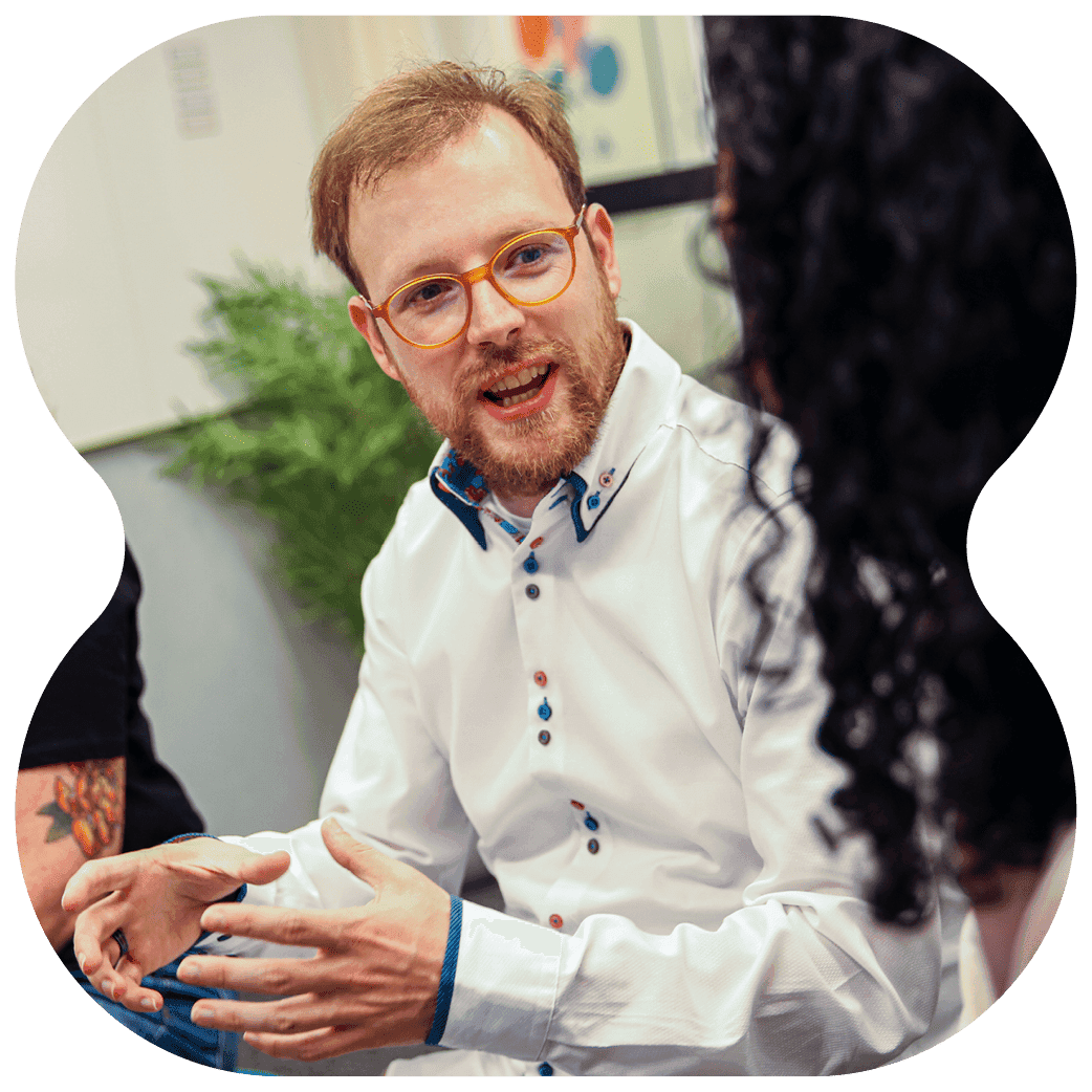 Person wearing a white shirt, gesturing with both hands while speaking in a group discussion.