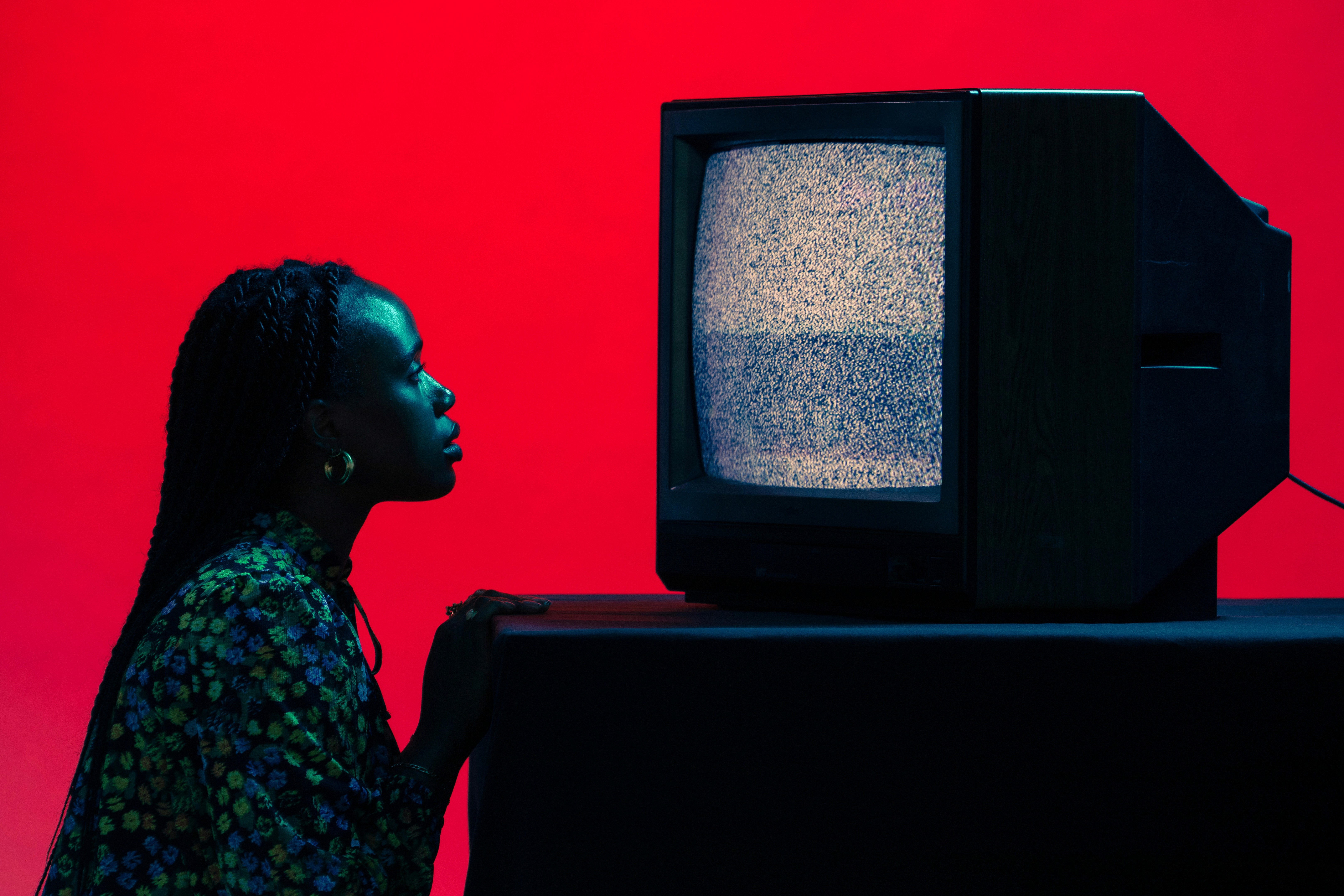 Person betrachtet einen Bildschirm mit Bildrauschen vor rotem Hintergrund – Sinnbild für das Lesen zwischen Signalen und das Verstehen von Nutzerwahrnehmung.