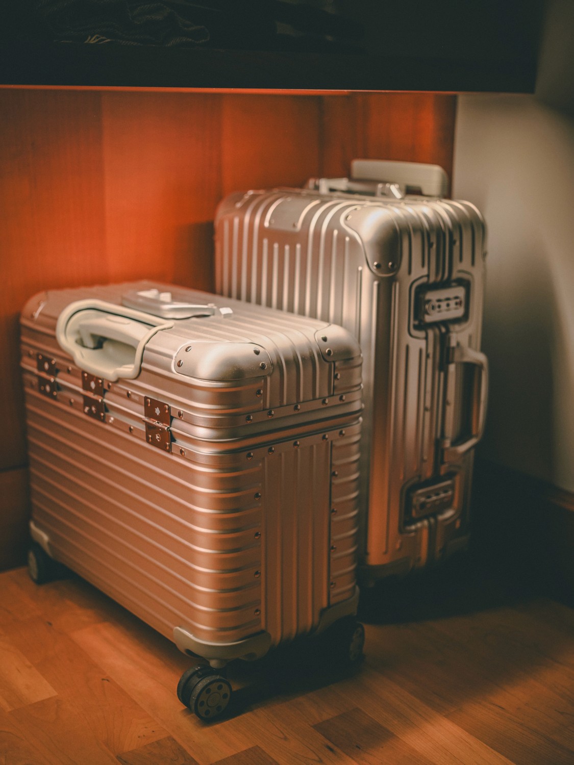Person in a hoodie and blue cap looking down under pink neon lights.